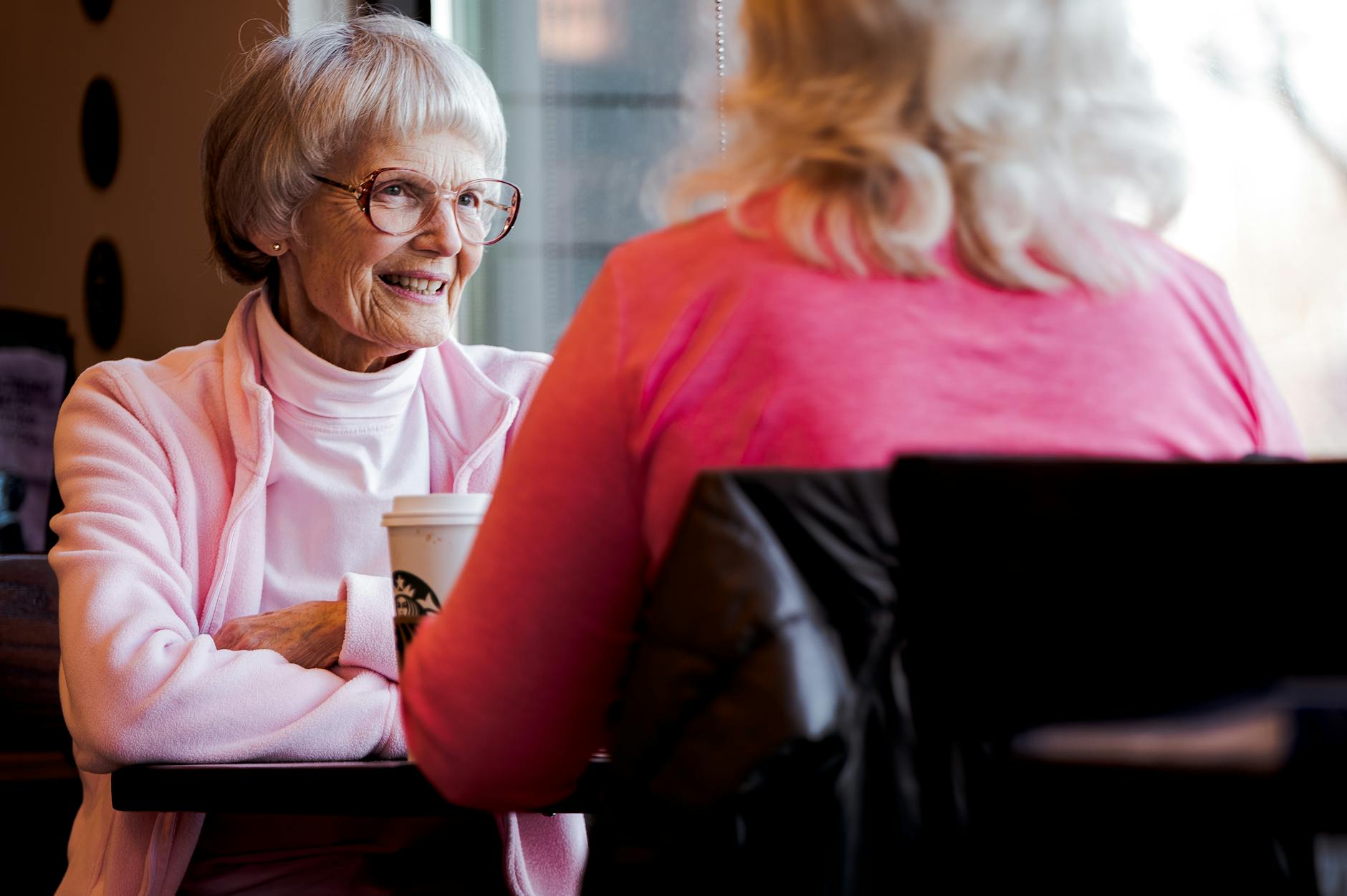 photo of old woman sitting while talking with another woman