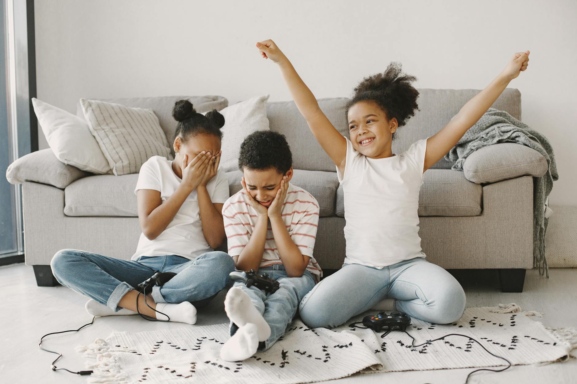 girl in white shirt and blue denim pants sitting beside a boy in red and white stripe shirt